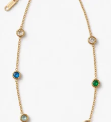 Gold plated station chain with bezel set colorful gemstones including red blue green purple and clear crystals on white background